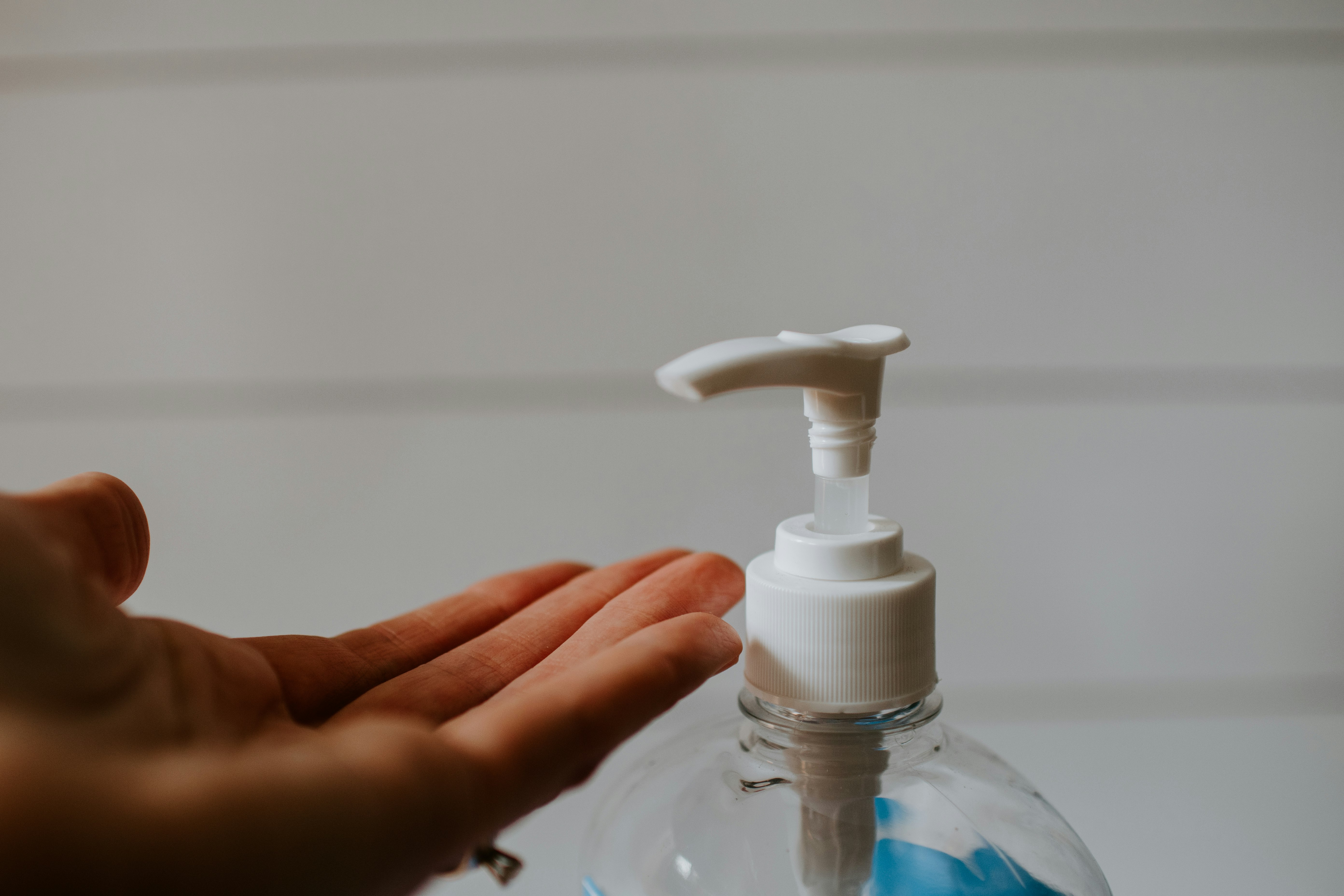 person holding white plastic pump bottle